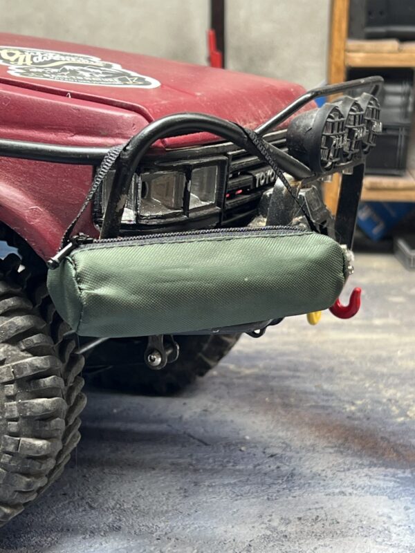 Runde grüne Campingtasche im Maßstab 1/10, montiert an der Stoßstange eines RC-Fahrzeugs. Perfektes Scale-Zubehör für Camping-Setups.